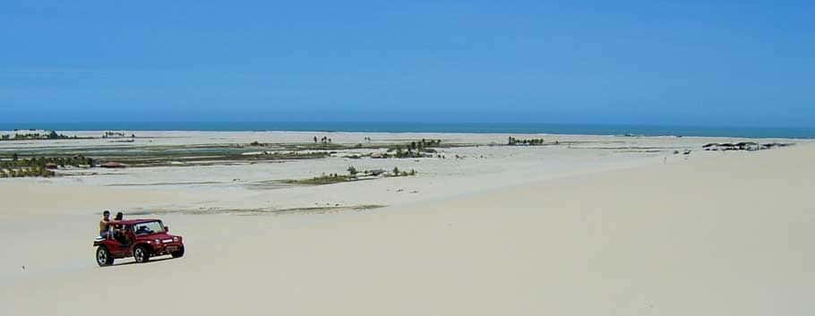 Buggy levando pessoas em seu interior em duna de areia: chegar a Canoa Quebrada