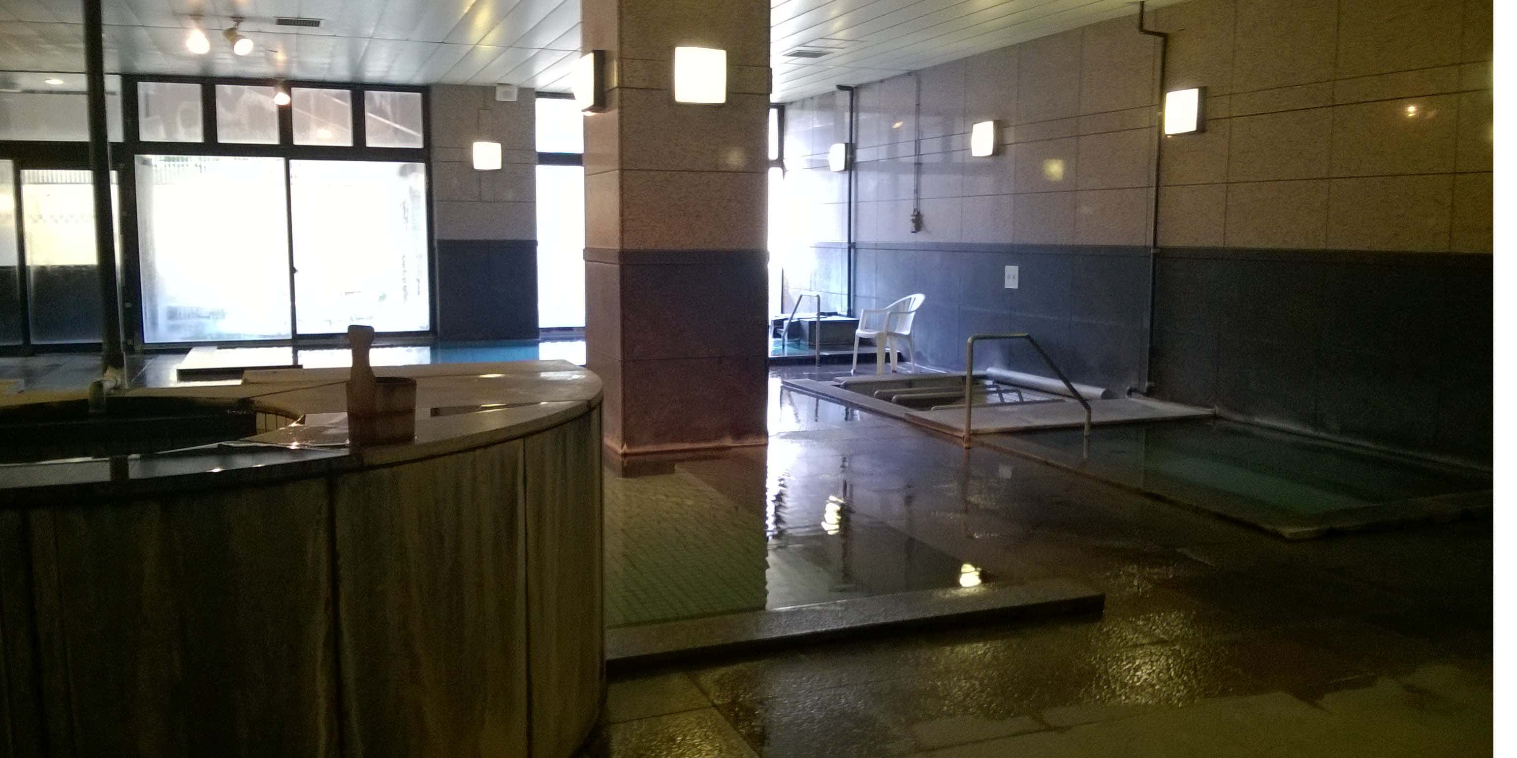 Sala com piscina para banho japonês, pilastras e muito vapor, uma casa de banho japonesa