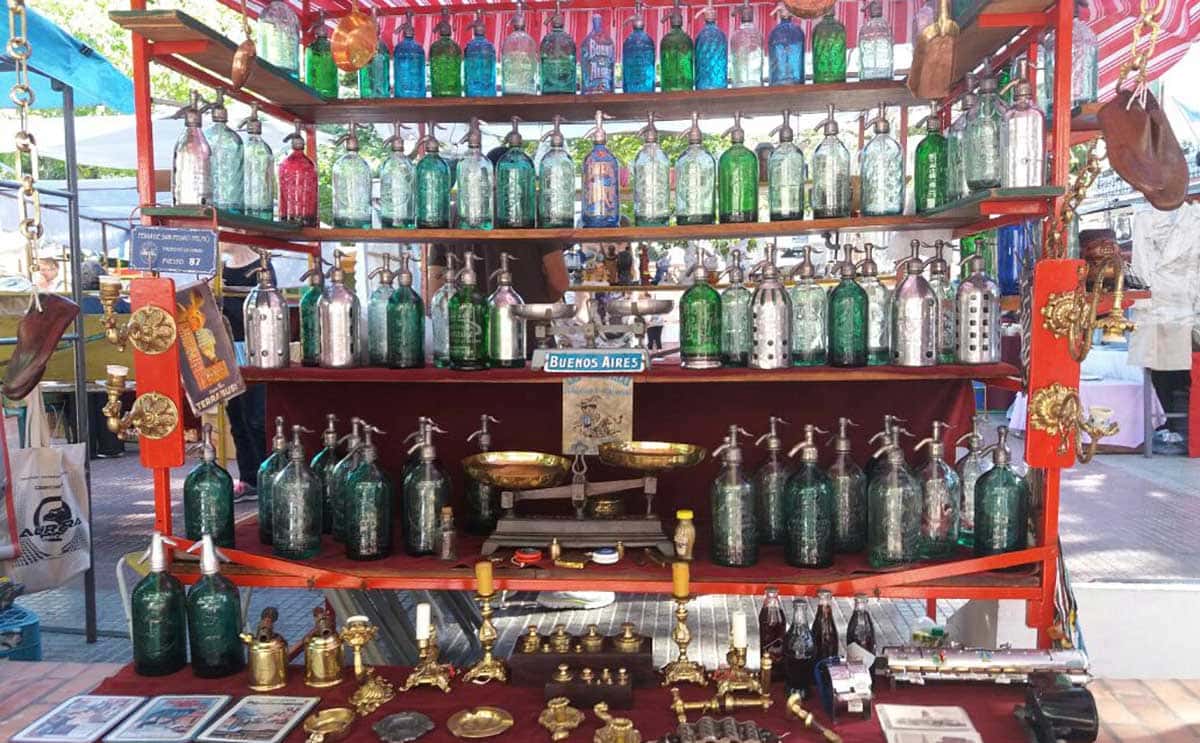 Barraca de feira com garrafas coloridas dispostas nas prateleiras