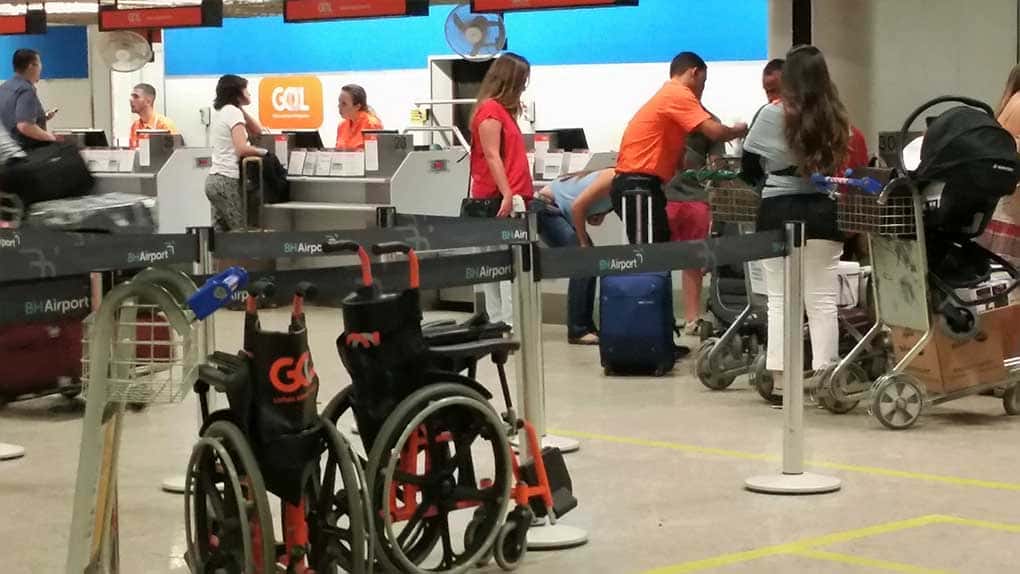 Área de embarque e cobrança de bagagem em aeroporto, com cadeiras para transportar passageiros em primeiro plano