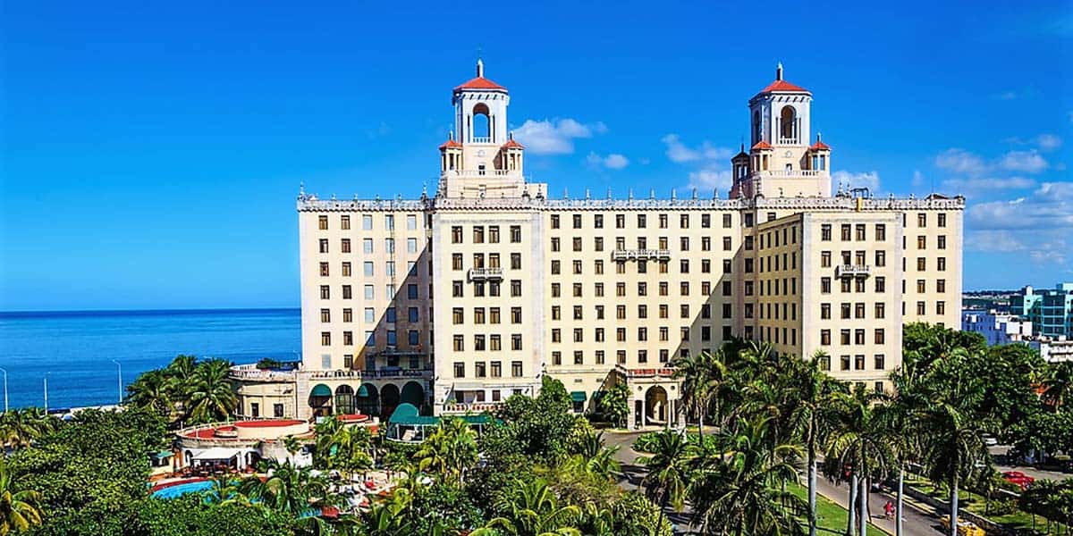 predio enorme com varias janelas, céu azul e ao fundo o mar. É o Hotel Nacional na cidade de Havana, Cuba, onde se hospedar em Havana