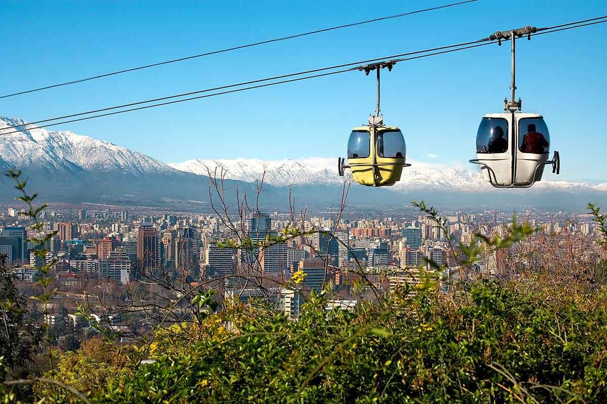 Dois teleféricos e ao fundo a cidade de Santiago e a Cordiheira dos Andes: o que fazer em santiago