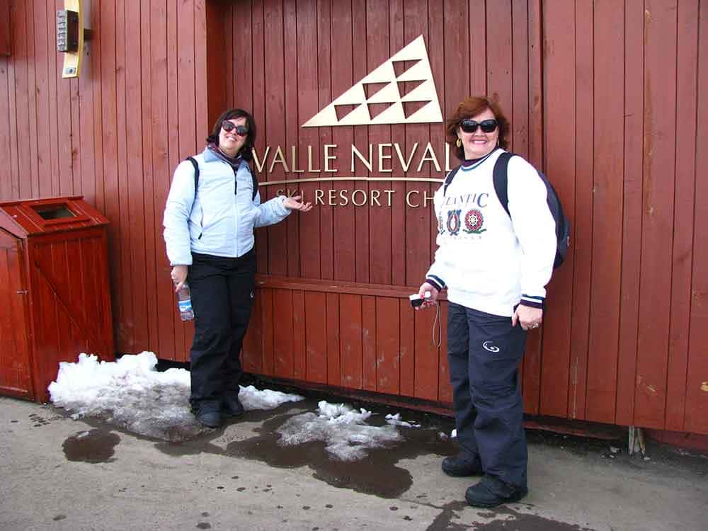 Duas mulheres mostram placa escrito Valle Nevado