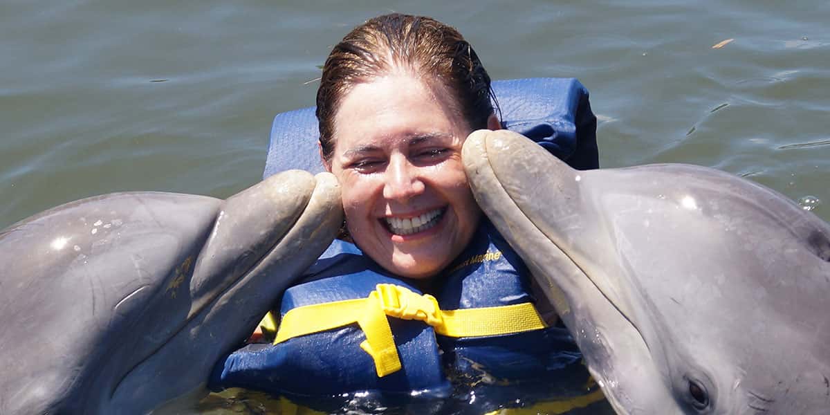 Patricia Lamounier sendo beijada por 2 golfinhos em varadero