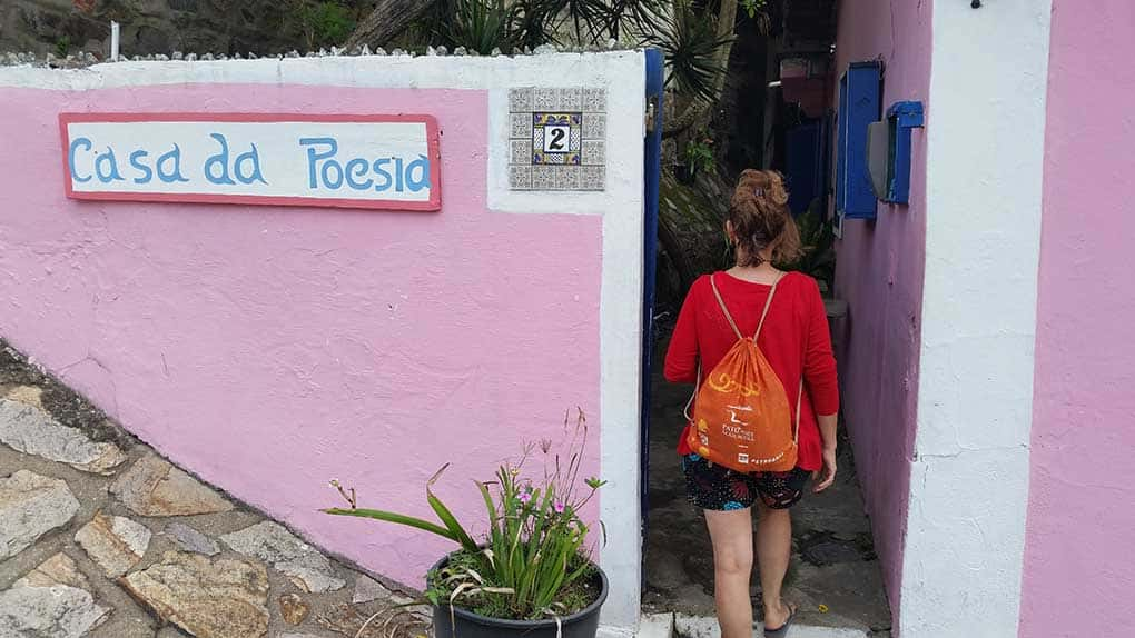 Entrada da Casa da Poesia, na cor rosa e com a placa Casa da Poesia, na praça histórica de Arraial do Cabo