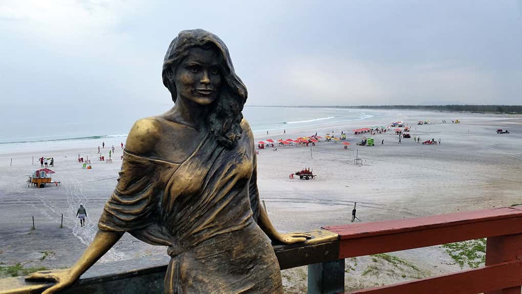 Escultura de mulher e praia ao fundo na Praia Grande em Arraial do Cabo