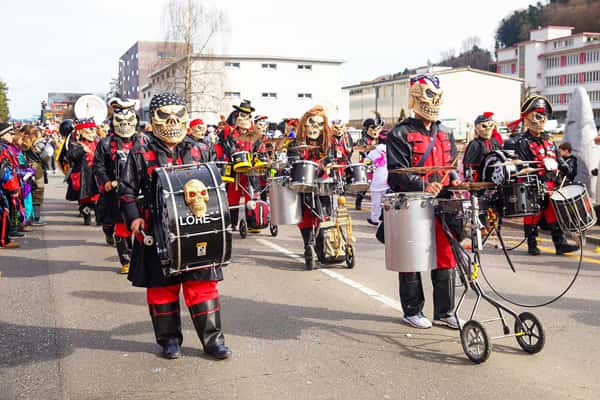 Homens mascarados tocam instrumentos em parada musical