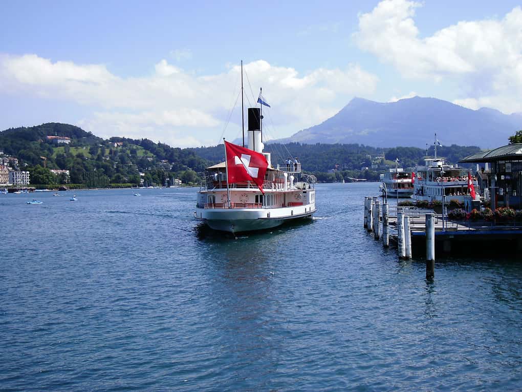 Barco no com bandeira da Suíça no rio e deck de madeira