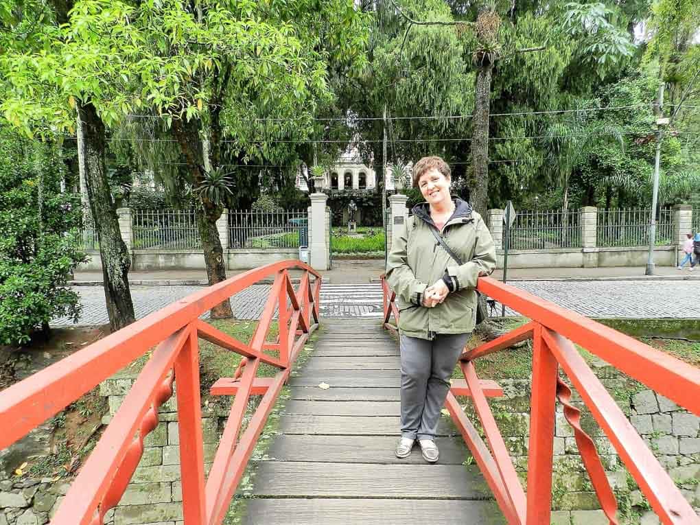 Mulher posa em pontezinha em frente aos jardins do Museu Imperial de Petropolis