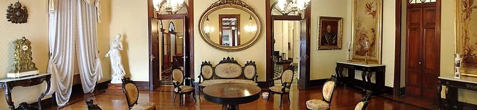 Sala com cadeiras mesa , duas portas e espelho ao fundo
