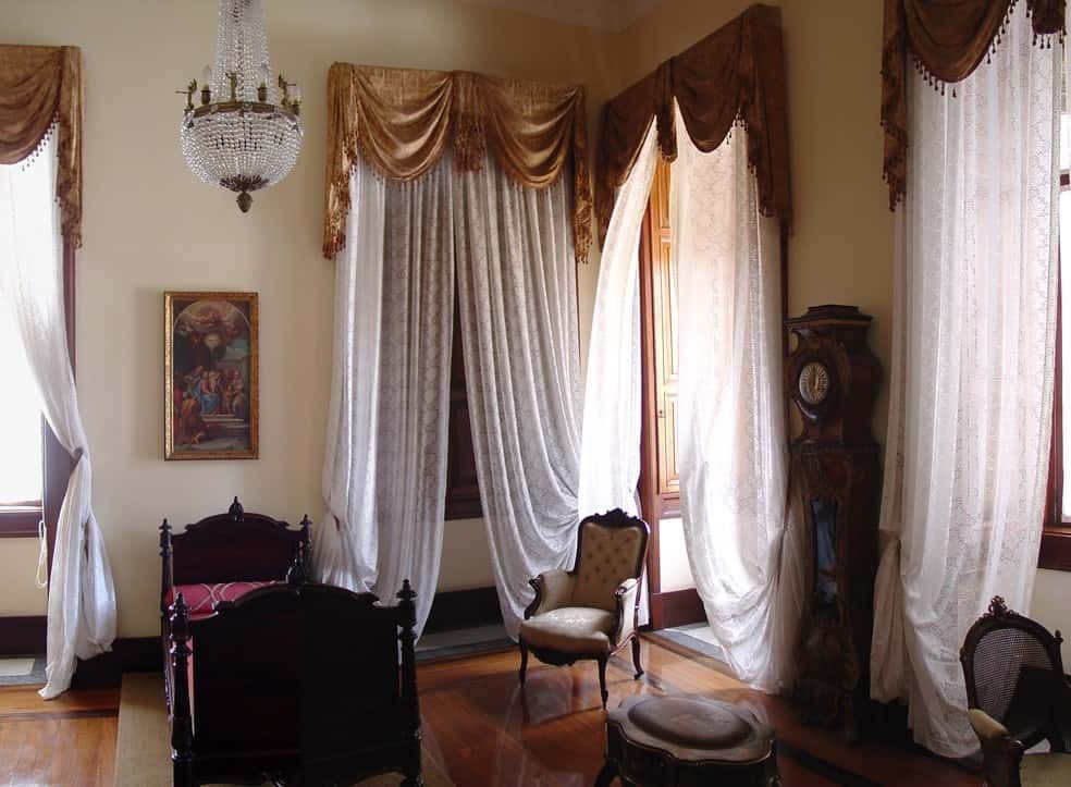 Quarto da Princesa Isabel, com a cama da princesa, cortinas, cadeira, um relógio, lustre, e quadro na parede